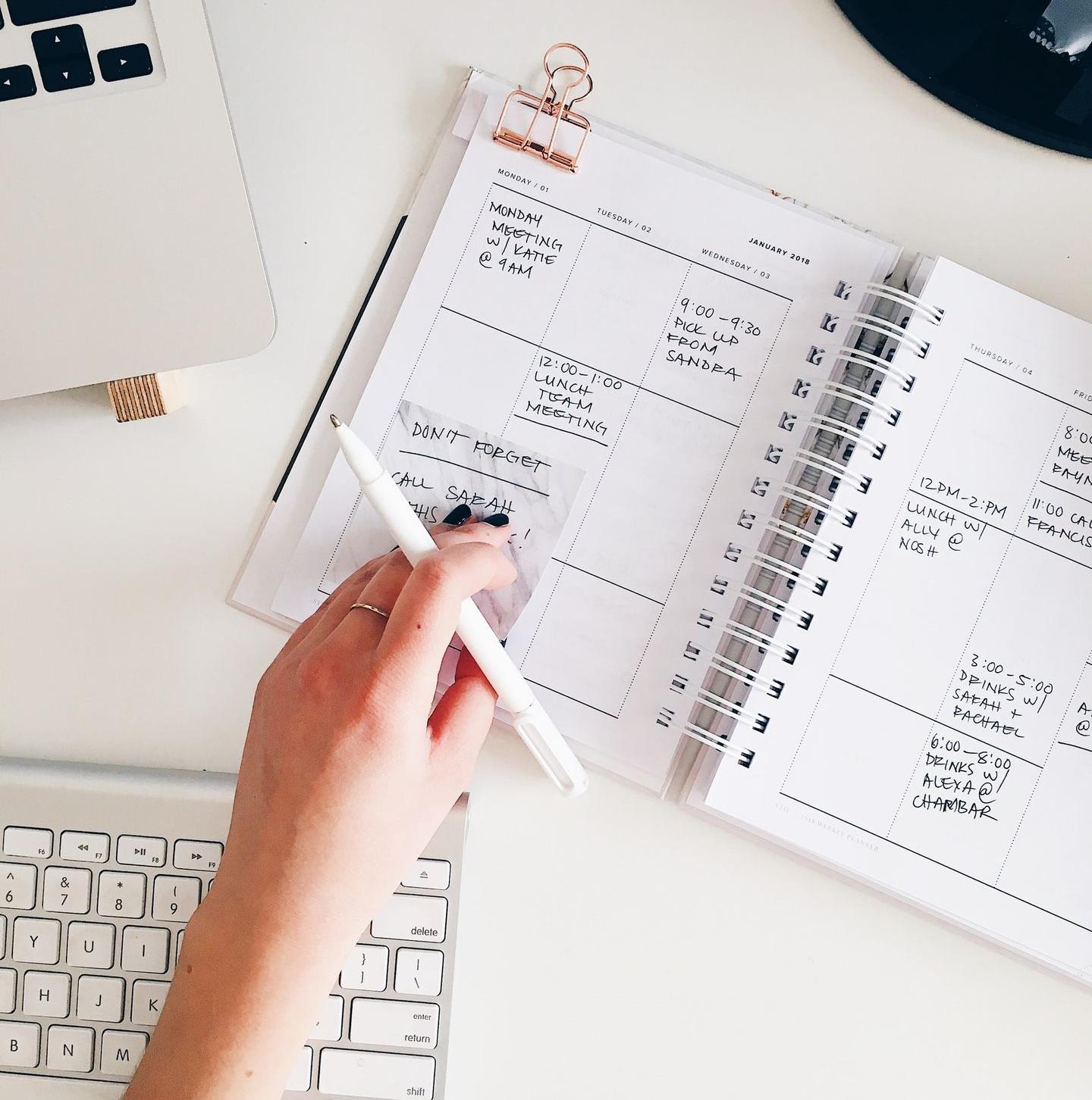 person holding notepad and pen flat lay photography